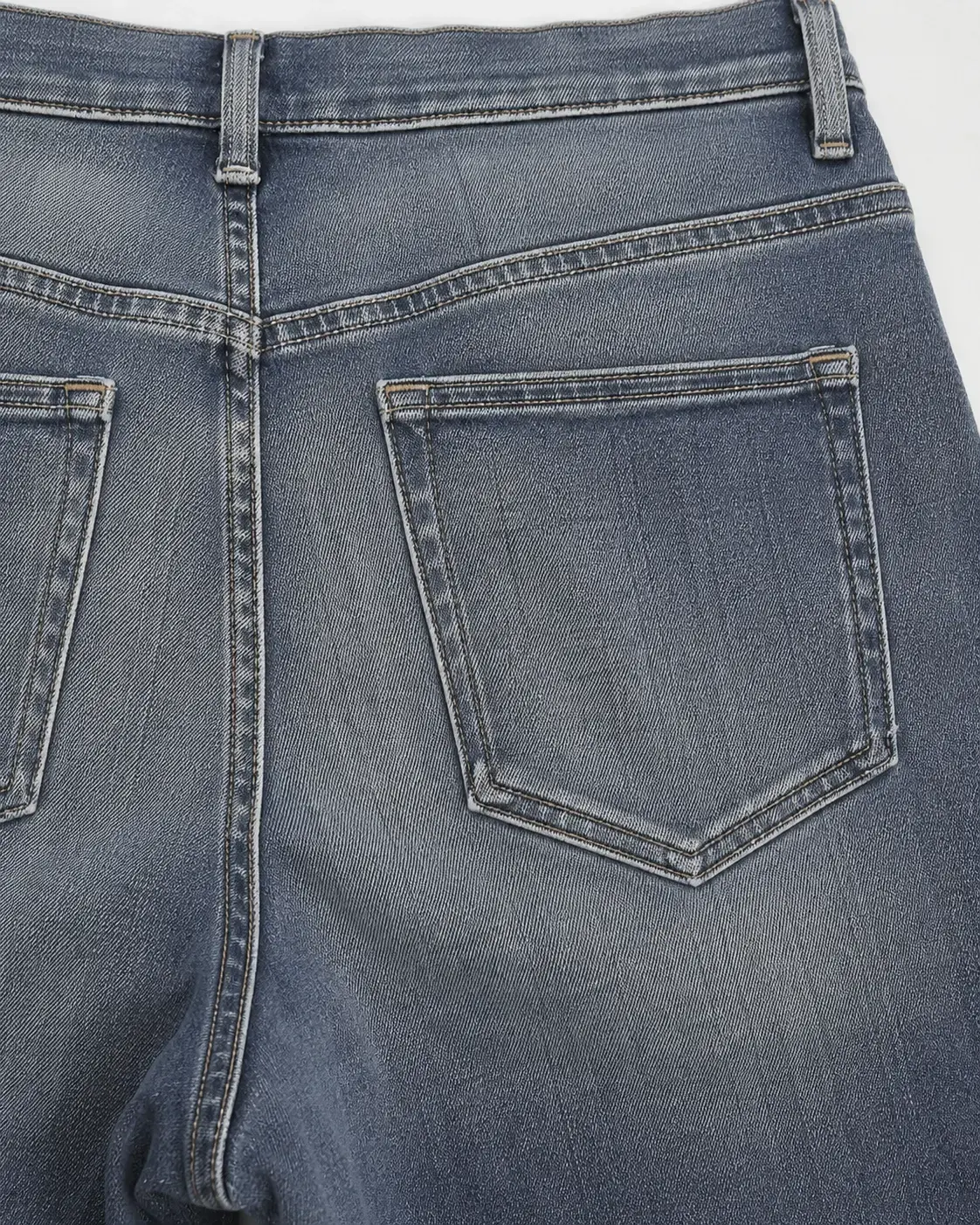 Back pocket and yoke construction on custom washed denim jeans